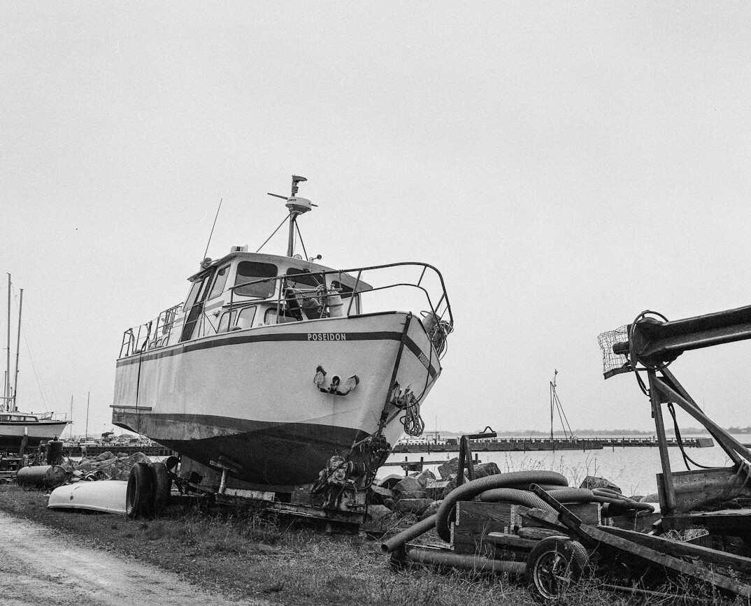 Elderly Danish fisherman mending nets beside his boat